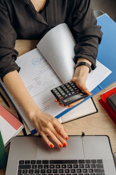 Person holding black calculator while using laptop