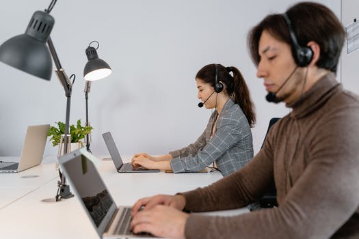 A man and a woman typing on their laptops