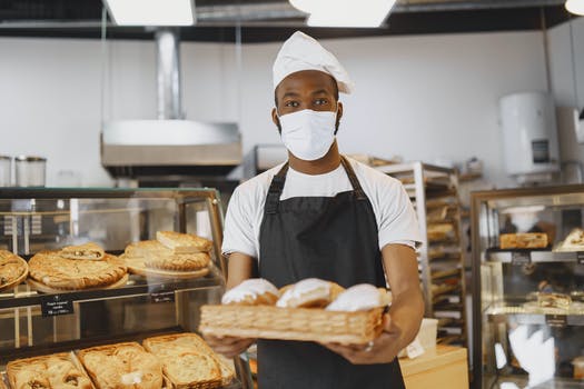 Man carrying a brown tray filled with bread