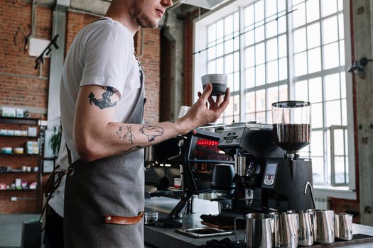 Man in white t shirt pouring coffee on black coffee maker