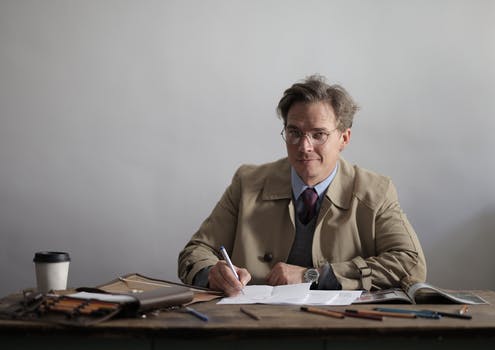 Serious male manager writing in papers while working at table