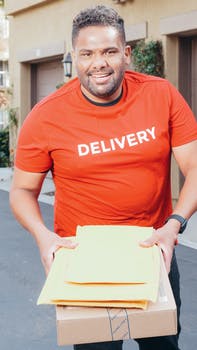 Man in red crew neck t shirt carrying a package and mails