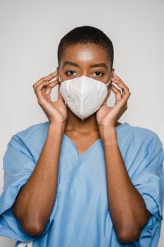 Black female doctor putting medical mask on face