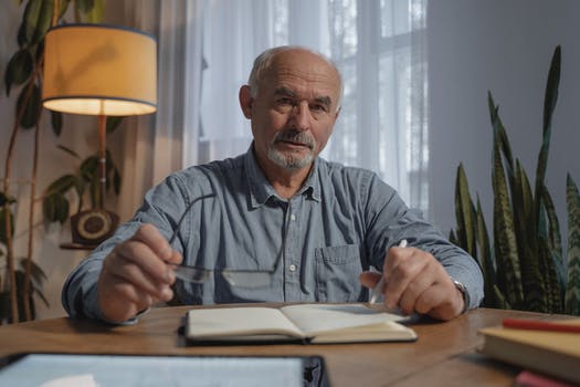 Man holding a pen and eyeglasses