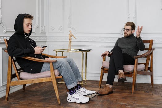 Man in black sweater and blue denim jeans sitting on brown wooden rocking chair