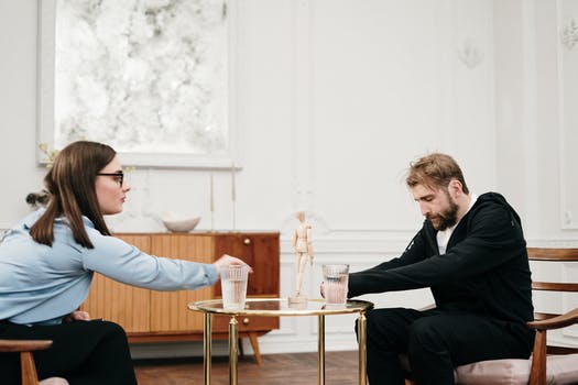 Man in black suit sitting on chair in front of man in black suit