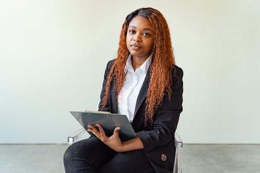 Woman in black blazer holding a clipboard