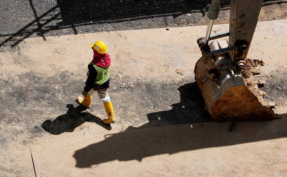 High angle photo of person walking near backhoe