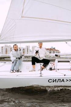 Man in black shirt and blue denim jeans standing on white boat