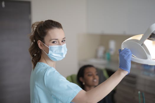 Young female dentist in mask and gloves examining patient in clinic