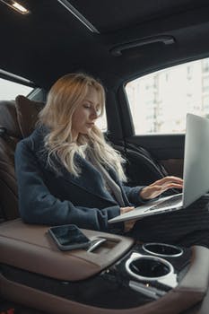 Woman in gray business suit sitting at the back seat of a luxurious car