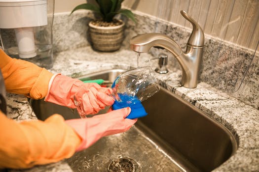 Person cleaning wine glass on sink