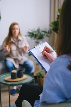 Crop psychologist writing on clipboard during psychotherapy session