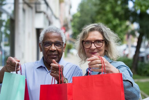 An elderly couple holding paper bags