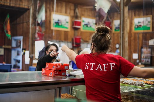 Cashier and customer in masks in cafe