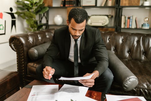 Man sitting on brown leather sofa looking at documents