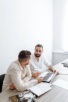 Man in white dress shirt using laptop computer beside man in white dress shirt