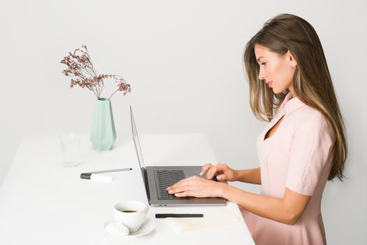 Woman in pink dress using laptop computer