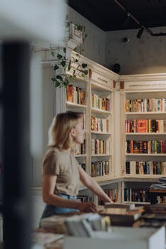 Girl in white t shirt standing beside brown wooden book shelf