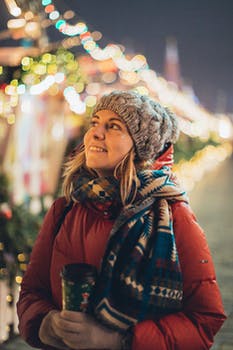 Woman in red jacket holding disposable cup