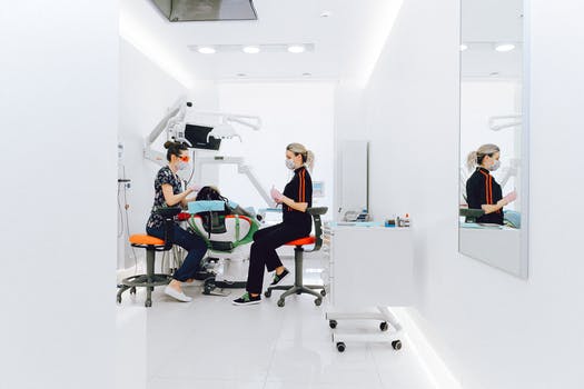 Female dentist and assistant examining patients teeth in clinic 