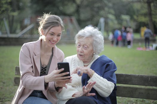 Cheerful senior mother and adult daughter using smartphone together 