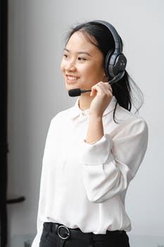 Photo of a woman smiling while holding the microphone of her headset 