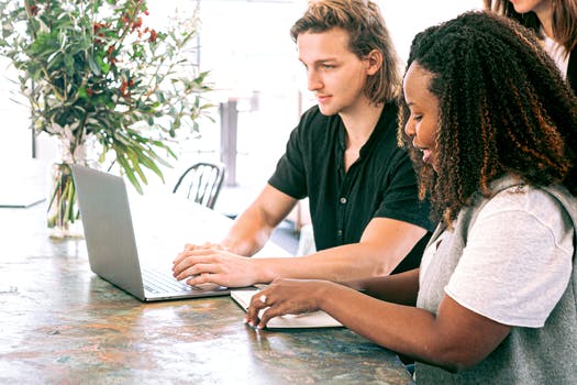 Man working on a laptop while woman takes notes