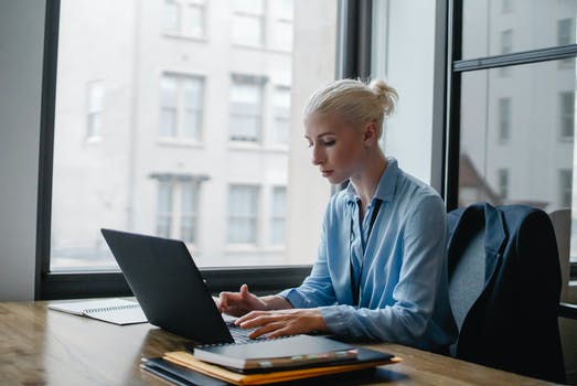 Serious woman typing on laptop in workspace