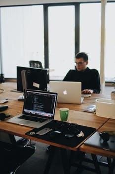 Man in black shirt sits behind desk with computers