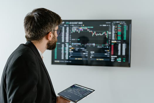 Man in black suit holding a digital tablet and looking at data on screen