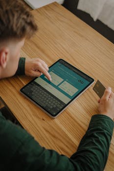 Close up shot of a person using an ipad while holding a credit card