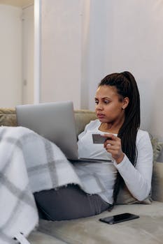 A woman using a laptop while holding a credit card