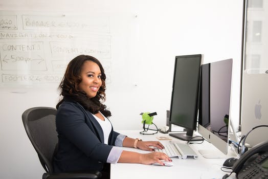 Woman in professional wear seated in front of monitor 