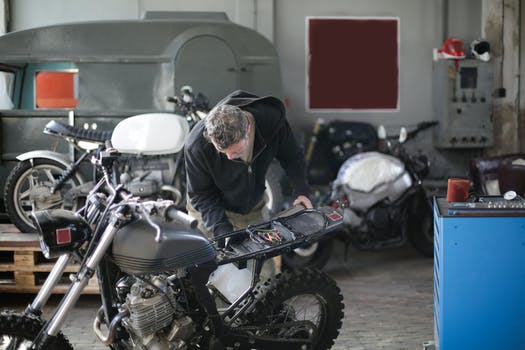 Anonymous adult male mechanic fixing motorbike in garage