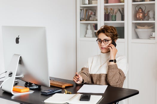 Serious female executive communicating on mobile phone in cozy office 