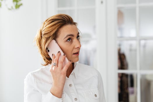 Woman in white button up shirt talking on the phone