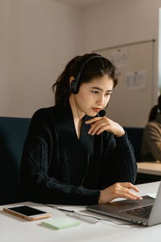 Woman with black headset and mouthpiece sitting in front of laptop