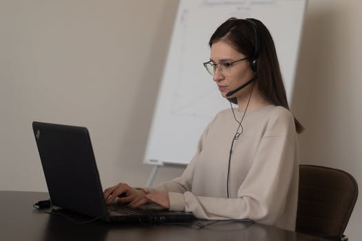 Female operator using netbook and headphones with microphone