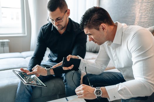 Two men pointing at ipad screen