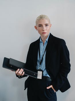 Confident businesswoman standing with folder against white wall