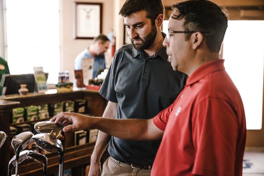 Two man standing near golf clubs