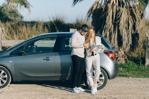 Couple standing beside a gray car