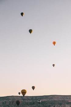 Hot air balloons flying in sky over highlands in daytime