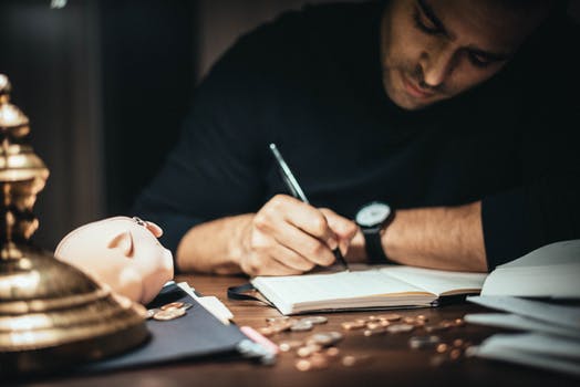 Focused man writing in account book at table